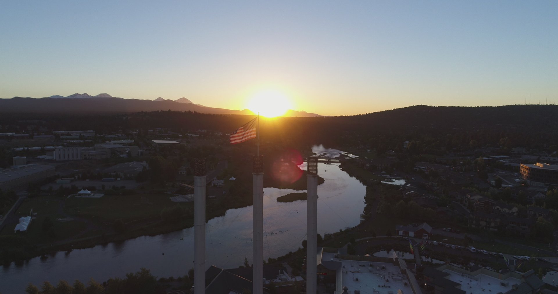 Wide aerial view of Bend with the Old Mill smokestacks, river, and mountains